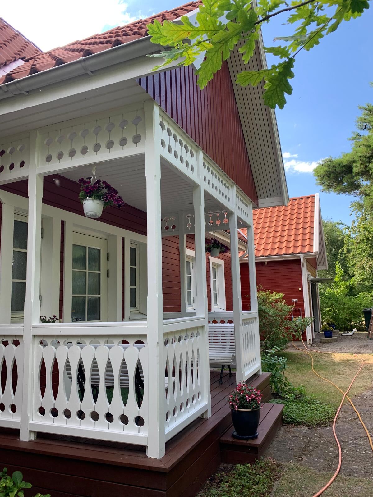 Röd fasad med målad veranda och vitmålade snickerier